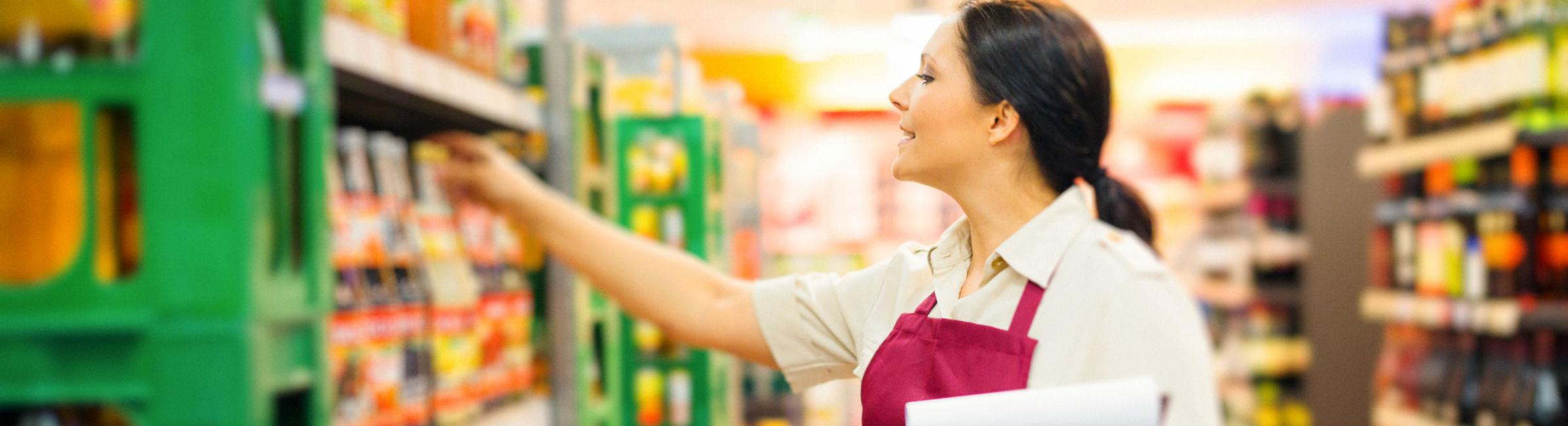 Un femme fait de la mise en rayon dans un supermarché